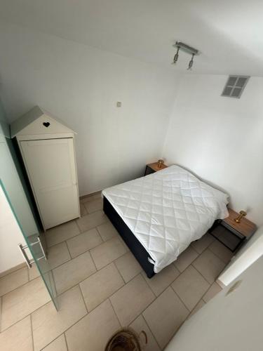 a white bedroom with a bed and a tiled floor at Residence Wembley with sea view in Middelkerke