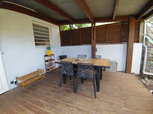 un patio con una mesa de madera y sillas en una terraza en Ti Kaz Bananier, en Saint-Gilles-les Hauts
