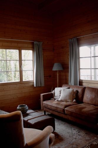 a living room with a couch and two windows at For-Rest Lodge de Hilkensberg in Broekhuizen