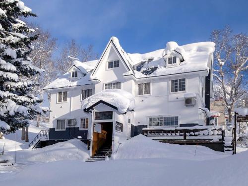 a large white house covered in snow at Pension Cotton Farm in Niseko