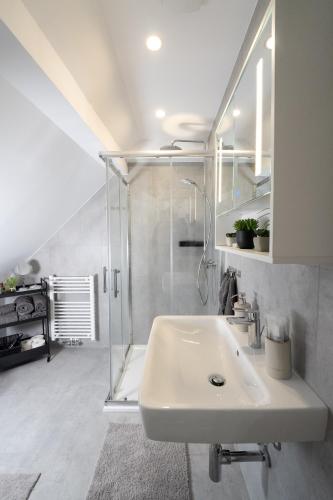 a white bathroom with a shower and a sink at Lumé35 in Hachenburg