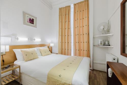 a bedroom with a large white bed and a window at Falcon Hotel in London