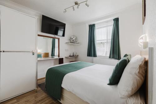 a bedroom with a large white bed with green sheets at Falcon Hotel in London
