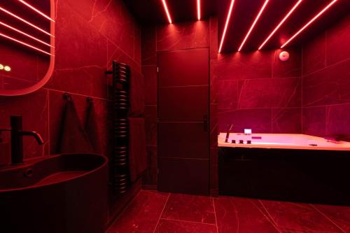 a red bathroom with a tub and a sink at loveroom le donjon in Anse