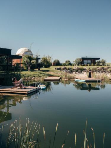 a person sitting on a dock on a lake at wecamp Reserva Alecrim in Santiago do Cacém