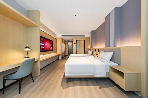a hotel room with two beds and a desk at Jin Yi X Hotel in Hekou