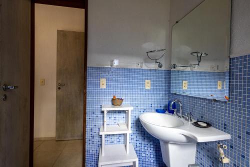 巴拉尤娜Casa Alto Padrao com 5 Suites e Jacuzzi Privativa的蓝色瓷砖浴室设有水槽和镜子