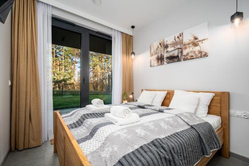 ein Schlafzimmer mit einem Bett und einem großen Fenster in der Unterkunft Vidok Apartamenty, Sun & Snow in Olsztyn