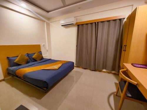 a bedroom with a bed and a window and a desk at Apex Inn Manyata in Bangalore