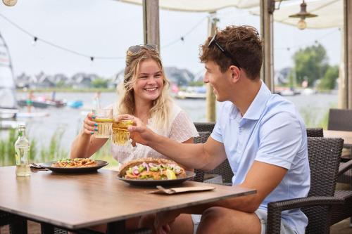 a man and a woman sitting at a table with food at RCN Vakantiepark de Potten in Offingawier