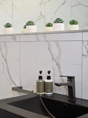 White Cottage Boutique Guesthouse في سواكوبموند: زجاجتان من الروائح تقعان على حوض الحمام