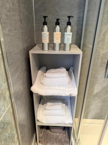 a shower stall with three bottles of soap and towels at Coastal Escape in Hamworthy