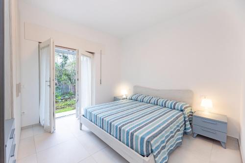 a white bedroom with a bed and a window at Il Cavo Suites - Elba Affitti in Cavo