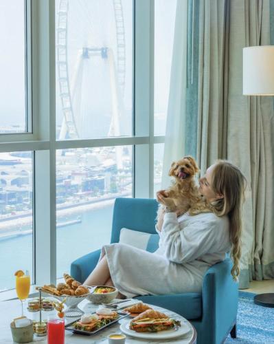 a woman sitting in a chair holding a dog at DoubleTree by Hilton Dubai Jumeirah Beach in Dubai
