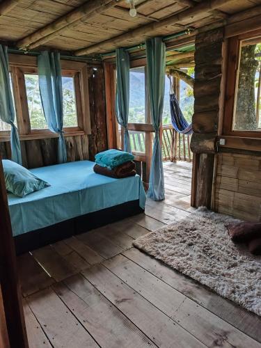 ein Schlafzimmer mit einem Bett in einer Blockhütte in der Unterkunft Casa Del Árbol Mirolindo Pijao Quindío in Pijao