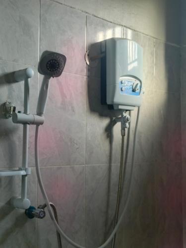 a shower in a bathroom with a soap dispenser on the wall at Haven Guest House in Kasese