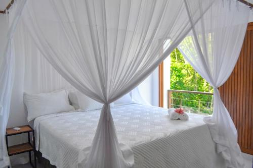 a bedroom with a canopy bed with a window at Casa Marah - Trancoso in Trancoso