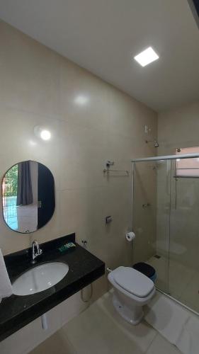 a bathroom with a toilet and a sink and a shower at Suítes Canaã in Capitólio