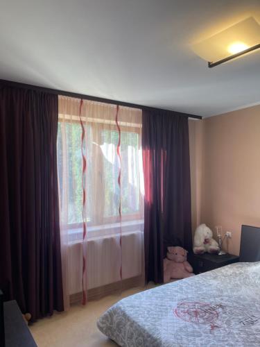 a bedroom with a bed and a window with curtains at Ava Apartment Pamporovo in Pamporovo