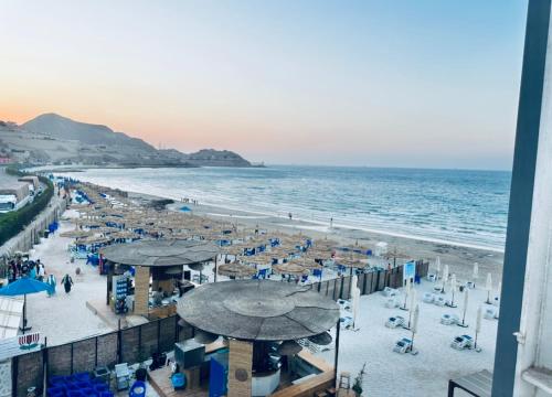 a beach with umbrellas and chairs and the ocean at Amer Group Villas and Chalets on the Pool in Ain Sokhna