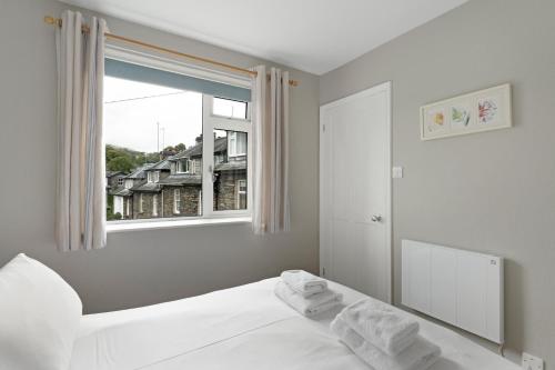 a bedroom with a white bed and a window at Rydal View Cottage in Ambleside