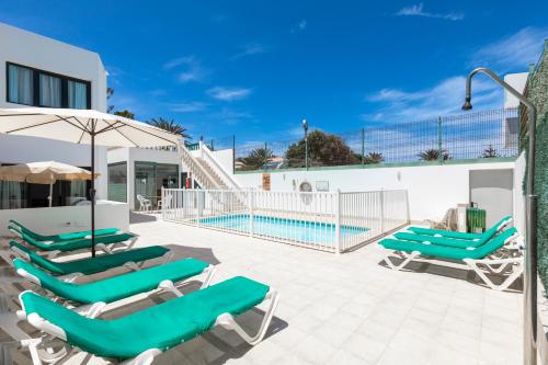 een patio met ligstoelen en een zwembad bij Apartamentos LIVVO Erika in Corralejo