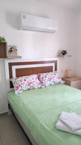 a bed with green sheets and pillows in a room at Unique and quiet TROPICKÝ PRÁZDNINOVÝ DŮM in Punta Cana