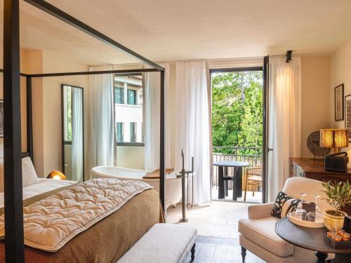 a bedroom with a bed and a balcony with a tub at L'Isle de Leos Hotel & Spa - MGallery Collection in LʼIsle-sur-la-Sorgue