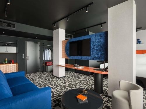 a living room with a blue couch and a tv at TRIBE Budapest Airport in Budapest