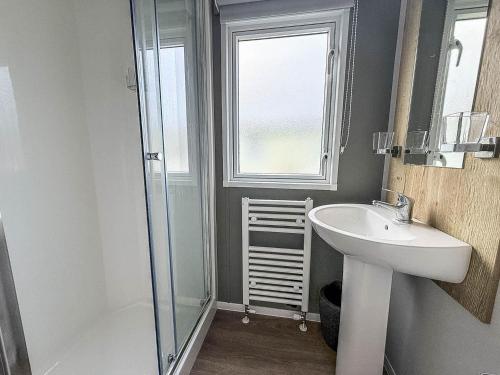 a bathroom with a sink and a glass shower at Beautiful 8 Berth Caravan With Decking At Naze Marine Holiday Park Ref 17344Br in Walton-on-the-Naze