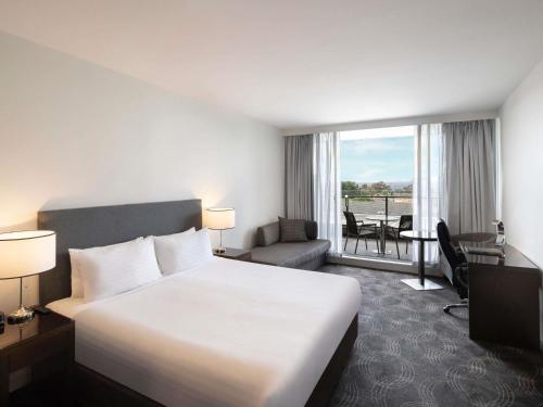 Una habitación de hotel con una cama grande y un balcón. en The Sebel Melbourne Kew, en Melbourne