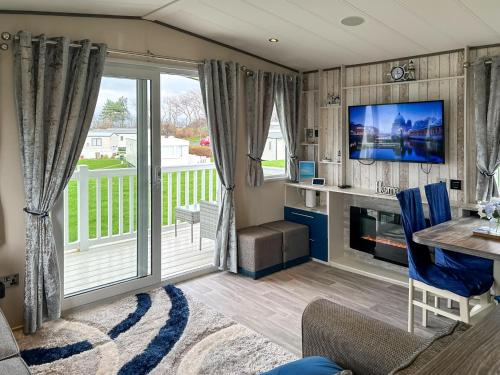 un soggiorno con porta scorrevole in vetro e TV di Ocean Bay View - Ukc7143 ad Ayr