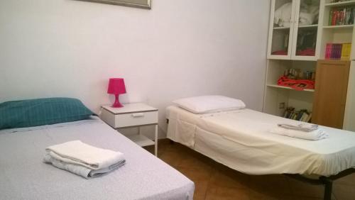 2 camas en una habitación con una lámpara rosa en una mesita de noche en Rita Room, en Florencia