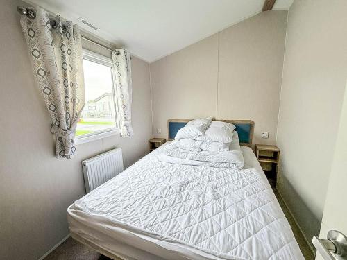 ein Schlafzimmer mit einem Bett mit weißen Laken und einem Fenster in der Unterkunft Spacious 8 Berth Caravan With Decking At Naze Marine In Essex Ref 17012Rd in Walton-on-the-Naze