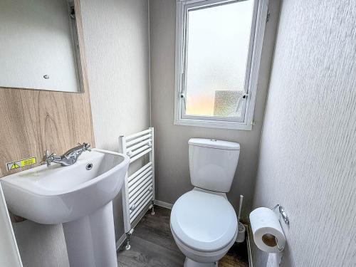 ein Badezimmer mit Toilette und Waschbecken und einem Fenster in der Unterkunft Spacious 8 Berth Caravan With Decking At Naze Marine In Essex Ref 17012Rd in Walton-on-the-Naze