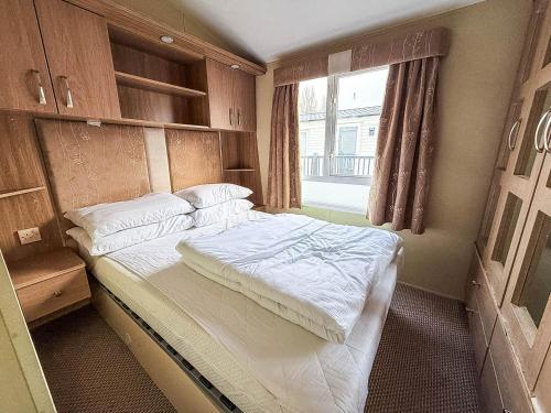 Un dormitorio con una cama grande con ventana. en Homely 8 Berth Caravan Near To The Beach In Walton-On-The-Naze Ref 17157P, en Walton-on-the-Naze