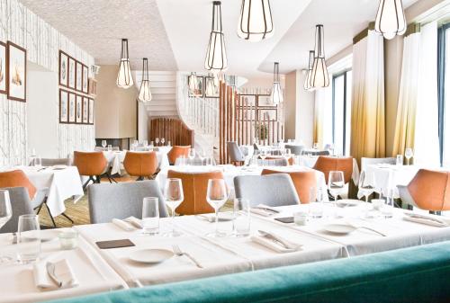 a restaurant with white tables and chairs and chandeliers at Hotel Le Saint Gelais in Angoulême