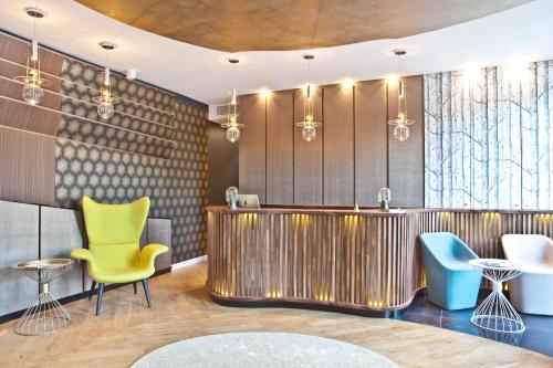 a lobby with a bar and yellow chairs at Hotel Le Saint Gelais in Angoulême