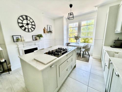 a white kitchen with a stove top island and a table at Seaside apartment in Bexhill