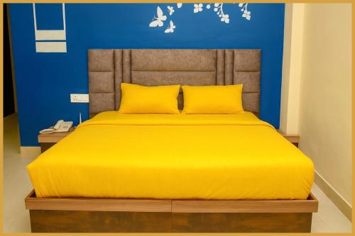 a yellow bed in a room with a blue wall at Mahakal Road The Shikhar #Avenue Residency Near Ujjain Junction Railway Station 500m-Mahakaleshwar Jyotirlinga - Free Wifi and Lift Facilities # Air Conditioning Rooms - Best Premium Hotel In Ujjain in Ujjain