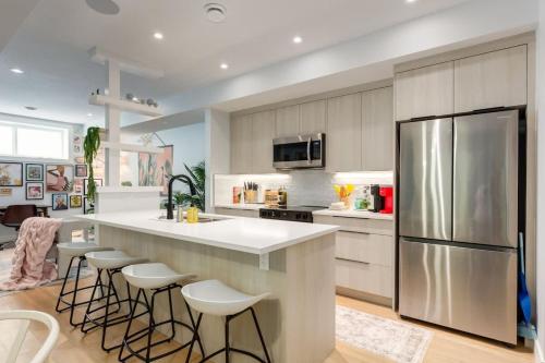 a kitchen with a bar with stools and a refrigerator at Santuario Kensington - Inner City Escape in Calgary