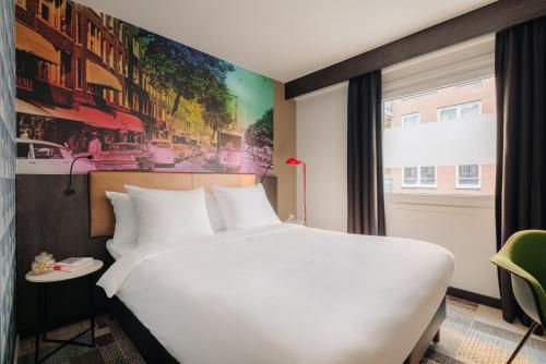 Un dormitorio con una cama blanca grande y una ventana en Leonardo Hotel Rotterdam Savoy, en Róterdam