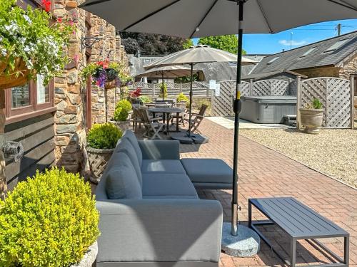 a patio with a couch and an umbrella and a table at Duvale Barn in Bampton