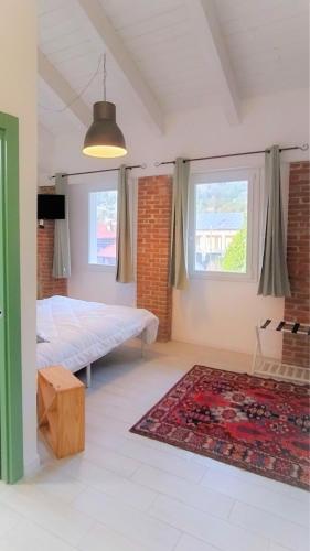 a bedroom with a bed and a rug and two windows at B&B La Barbatella in Palazzo Canavese