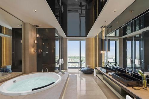利雅德Fairmont Riyadh的浴室配有大型浴缸和玻璃墙。