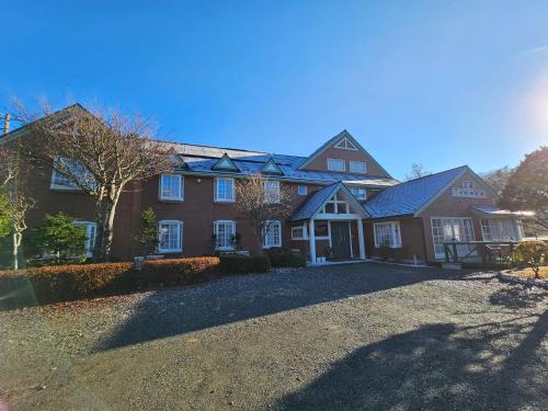 a large house with a driveway in front of it at Pension Avenue in Yamanakako