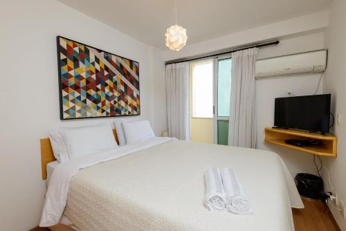a bedroom with a white bed and a flat screen tv at Flat c/ Limpeza Diária e Estacionamento - LB507 in Rio de Janeiro