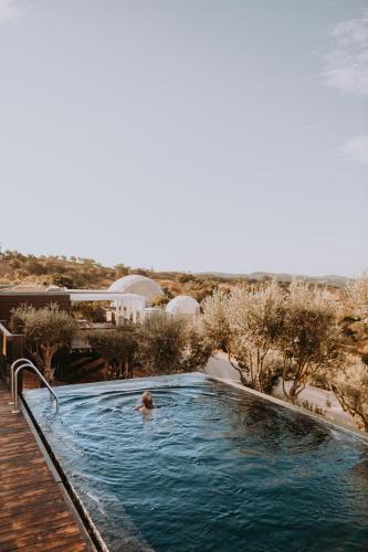 a person swimming in a swimming pool in a resort at wecamp Reserva Alecrim in Santiago do Cacém