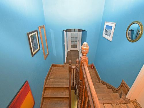 un pasillo con paredes azules y una escalera de madera en Sunnycote, en Arnside