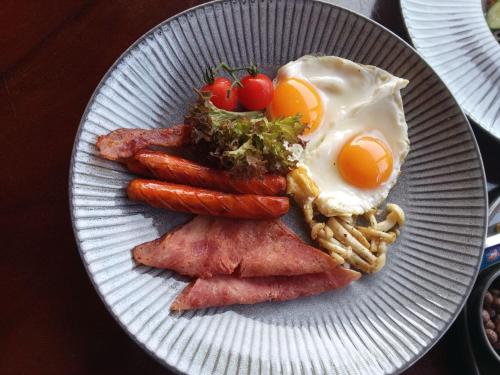 um prato de comida com ovos, bacon e tomates em Royal C Resort em Koh Rong Island